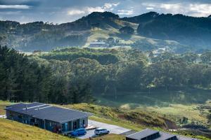une maison avec deux voitures garées devant une montagne dans l'établissement Hot Water Beach Lookout B&B, à Hahei