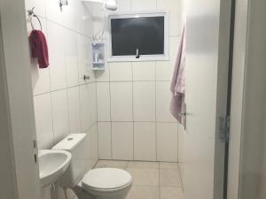 TV y baño con aseo y lavamanos. en Apartamento Praia de Boraceia - Litoral Norte SP en Boracéia
