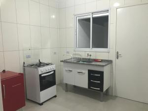 cocina blanca con fogones y fregadero en Apartamento Praia de Boraceia - Litoral Norte SP en Boracéia