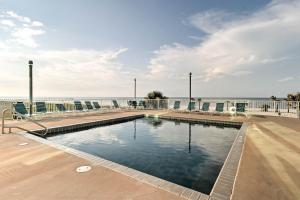 a swimming pool with chairs and the ocean in the background at Beachfront Condo with Pool Access in Biloxi! in Biloxi