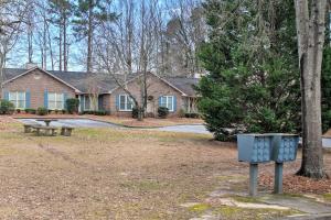 a house with a bench and a trash can in a yard at Cozy Greenwood Condo with Patio - 2 Mi to Downtown! in Greenwood