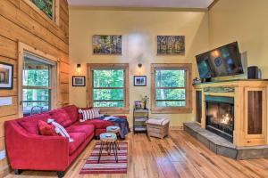a living room with a red couch and a fireplace at Romantic Asheville Area Cabin with Deck and Hot Tub! in Leicester