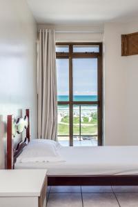 a bedroom with two beds and a large window at Apart Hotel Porto Príncipe in Cabo Frio