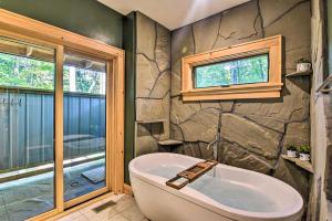 a bathroom with a bath tub and a window at Romantic Asheville Area Cabin with Deck and Hot Tub! in Leicester +30 photos