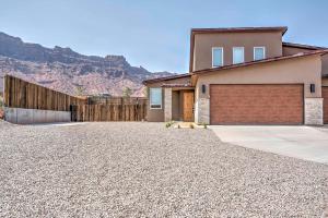 a house with a garage and a mountain in the background at Modern Moab Townhome with Private Hot Tub and Patio! in Moab