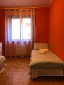 a bedroom with orange walls and a bed with a window at Trento House in Trento