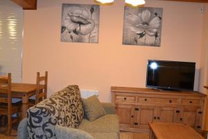 uma sala de estar com um sofá e uma televisão de ecrã plano em Casa rural La Senderilla em Ávila