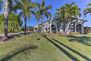ein Haus mit Palmen davor in der Unterkunft Canalfront Cape Coral Home with Pool and Dock! in Cape Coral
