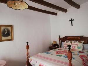- une chambre dotée d'un lit avec une croix sur le mur dans l'établissement Cal Munte, à Mont-roig