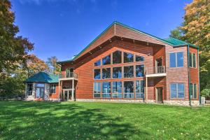 uma grande casa de madeira com um relvado verde em Waterfront Lake Mille Lacs Lodge with Deck and Grill! em Isle