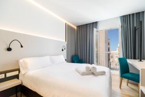 Habitación de hotel con cama, escritorio y ventana en Dormos Hotel, en Cádiz