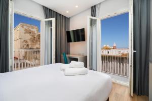 a hotel room with a bed, tv and a window at Dormos Hotel in Cádiz