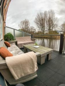 a patio with a table and a bench and water at 1 room studio with wonderful view in Den Helder