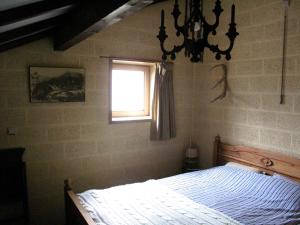 a bedroom with a bed with a window and a chandelier at Le Vieux Sart 32 Coo in Stavelot