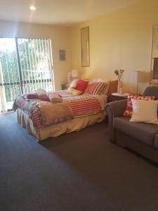 a bedroom with a large bed and a couch at Perfect Small Bay Peaceful Beach. Great Fishing Boating Oysters in Ohingaroa