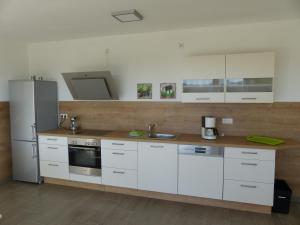 a kitchen with white cabinets and a stainless steel refrigerator at Komfort Ferienwohnung Wolfhagen in Wolfhagen