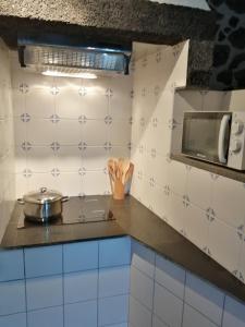 a kitchen with white tiled walls and a stove at Casa da Alícia in Feiteira