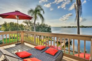 une terrasse avec une chaise, un parasol et l'eau dans l'établissement Lakefront Florida Retreat - Pool Table and Boat Dock, à Lake Placid