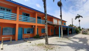 an orange building with palm trees in front of it at Pousada Gaucha Caiobá in Matinhos