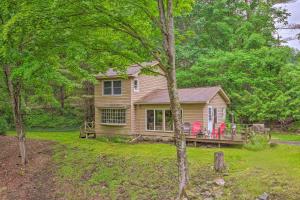 a house with a deck and chairs in the yard at The Mill River Cabin with Fireplace and River View! in Mill River