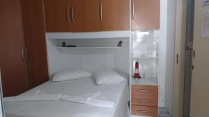 um pequeno quarto com uma cama e um frigorífico em Apartamentos Andréia em Florianópolis