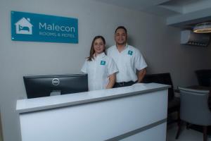 a man and woman standing next to a reception desk at Malecon Premium Rooms & Hotel in Santo Domingo
