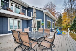 a patio with a table and chairs and an umbrella at Waterfront Charlevoix Home with Kayaks and Fire Pit! in Ellsworth