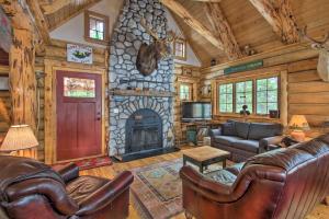 a living room with leather furniture and a stone fireplace at Waterfront Conway Vacation Rental with Deck! in Conway