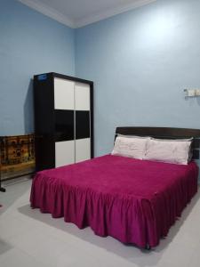 una camera con un letto e una coperta viola di Homestay Seri Nipah Perlis a Kangar