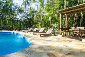 a swimming pool with lounge chairs and a table at Pousada Arapassu in Eldorado