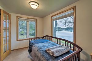 a bedroom with a bed and two large windows at Lakefront Home with Seasonal Dock - 2 mi to Skiing! in Wautoma