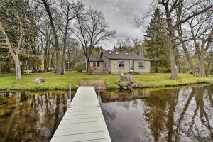 a wooden bridge over a river in front of a house at Lakefront Home with Seasonal Dock - 2 mi to Skiing! in Wautoma
