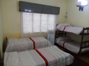 2 camas individuales en una habitación con ventana en MERCEDES CASA DEL HUM, en Mercedes