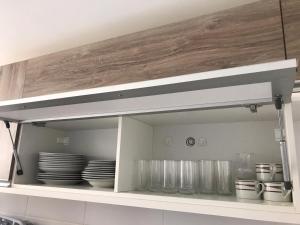 a kitchen shelf with plates and dishes in it at Mediterrâneo 507 - Todo Equipado, Ar Condicionado, Churrasqueira na Varanda, Internet Fibra 600MB, Estacionamento Grátis in Cabo Frio