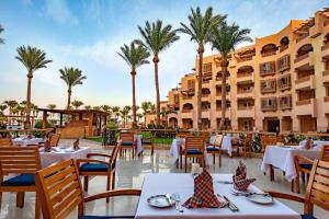 ハルガダにあるContinental Hotel Hurghadaのテーブルと椅子とヤシの木があるレストラン