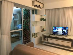 sala de estar con sofá, TV y ventana en JTR-Condominio a Beira Mar, en Maceió