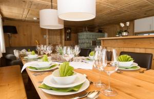 a wooden table with glasses and plates on it at Schwarzmann's Ferienwohnungen in Schröcken