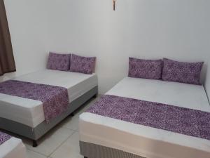 two beds in a room with purple and white at Casa de Temporada Illôa in Canindé de São Francisco