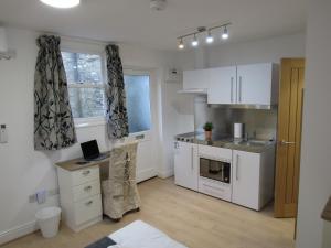 a kitchen with white cabinets and a desk in it at The Tas Suites - Tas Accommodations in Cambridge
