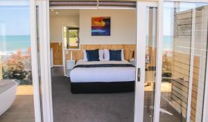 a bedroom with a bed and a view of the ocean at Belt Road Seaside Holiday Park in New Plymouth