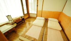 Habitación con 2 camas, mesa y ventana. en Hanok Story Guesthouse en Jeonju