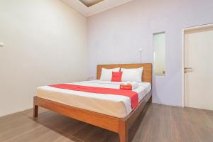 a bedroom with a large bed with red pillows at RedDoorz Resort Syariah near D'Castello Ciater Subang in Subang