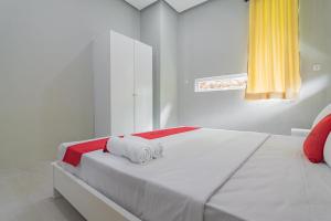 een witte slaapkamer met een bed met handdoeken erop bij RedDoorz Resort Syariah near D'Castello Ciater Subang in Subang