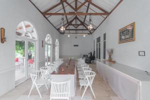 a dining room with white chairs and a long table at RedDoorz Resort Syariah near D'Castello Ciater Subang in Subang