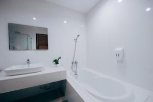 
a bathroom with a tub, sink, mirror and bathtub at Nana Beach Hotel & Resort in Pathiu
