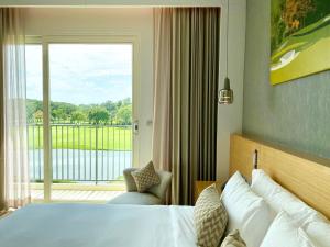 a hotel room with a bed and a large window at Eastin Thana City Golf Resort Bangkok in Samutprakarn