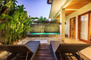 einen Pool in der Mitte einer Terrasse mit zwei Stühlen in der Unterkunft Kuta Legian Villa by Kamara in Legian