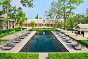 una piscina all'aperto con sedie a sdraio e ombrelloni di Avani+ Luang Prabang Hotel a Luang Prabang