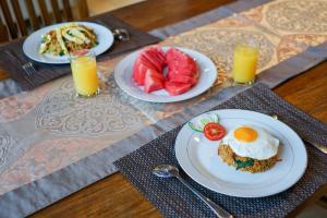 a table with two plates of food and two glasses of orange juice at Baliana Villa Legian in Legian