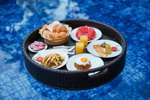 a table with plates of food and drinks in a basket at Baliana Villa Legian in Legian
